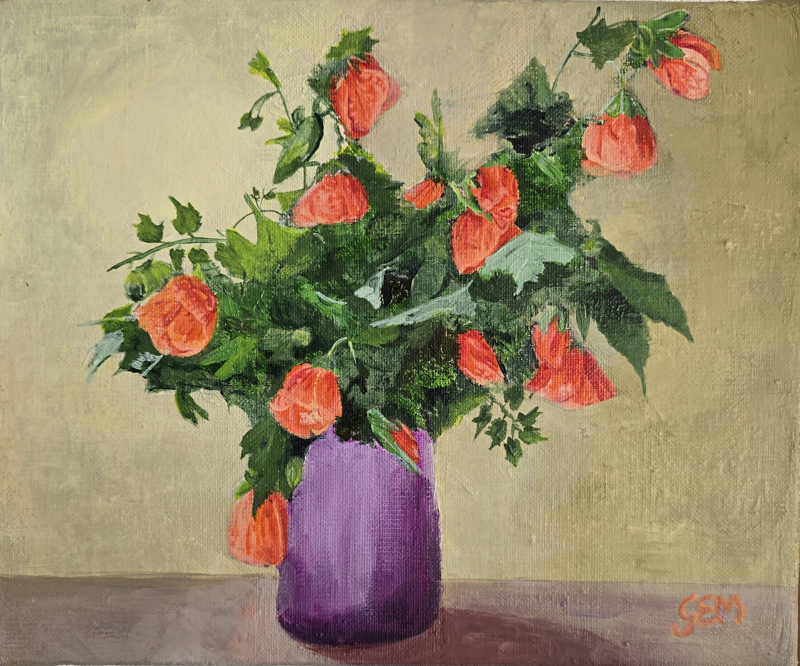a blue vase on the table with a bouquet of abutilons